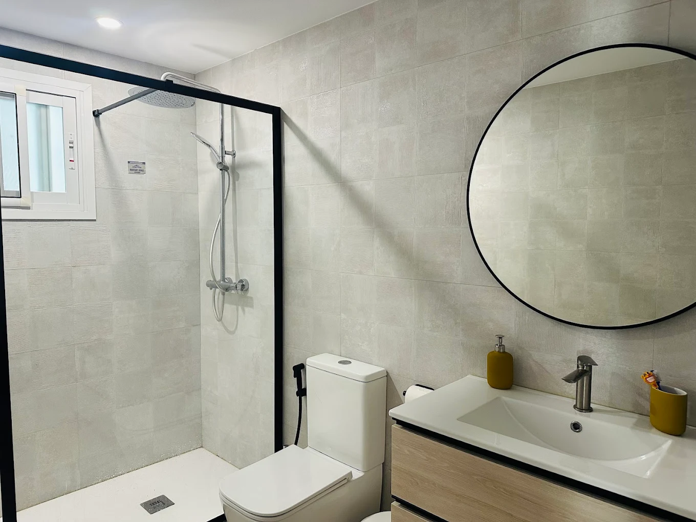Baño con ducha enrasada y espejo redondo — reforma Torreblanca