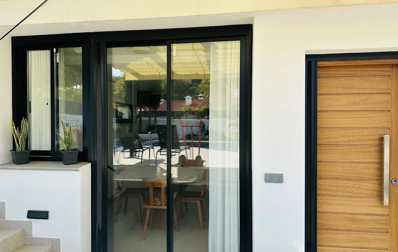 Carpintería exterior de aluminio negro y puerta de madera — reforma Torreblanca