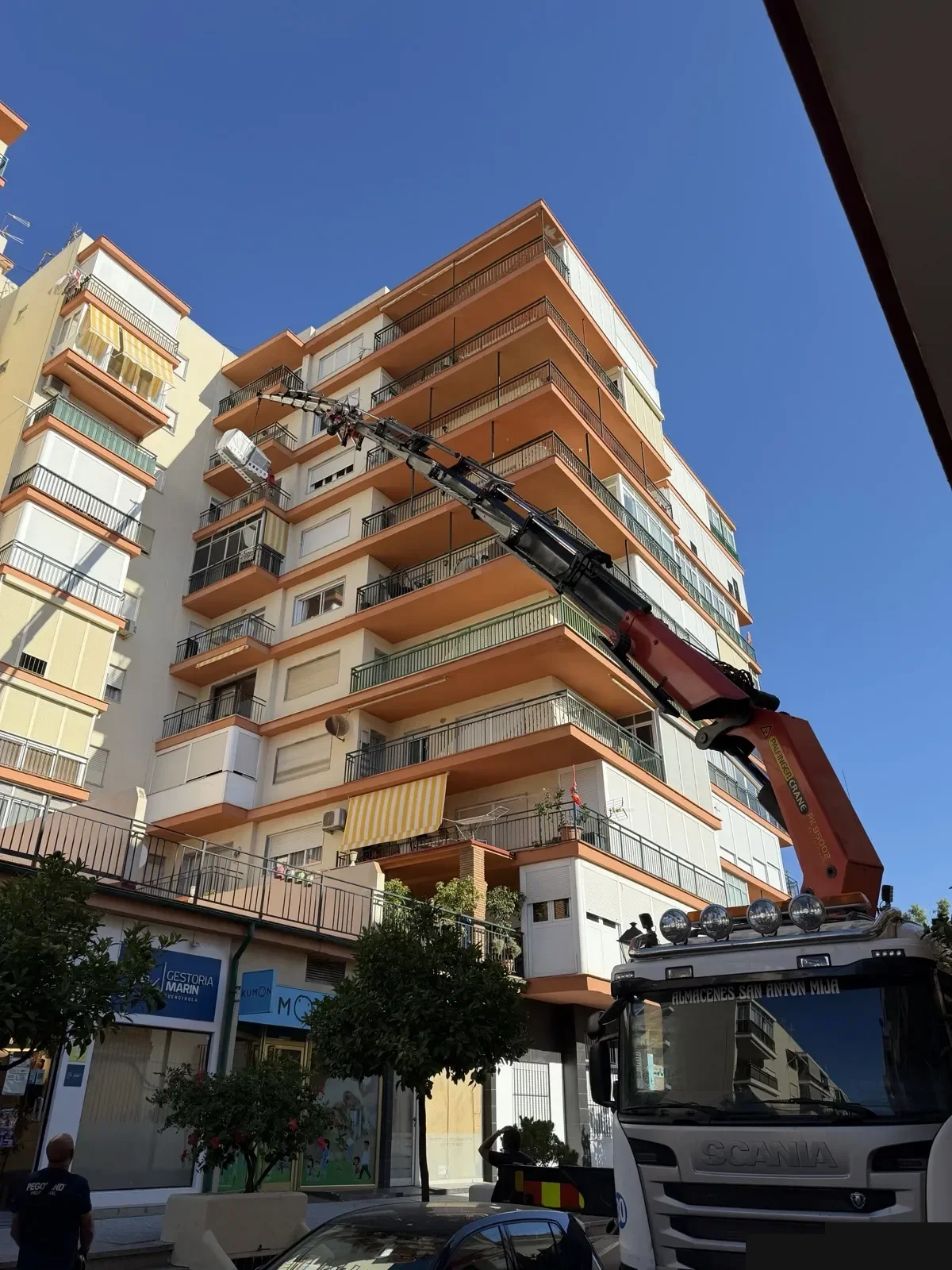Grúa de camión subiendo material a un piso alto